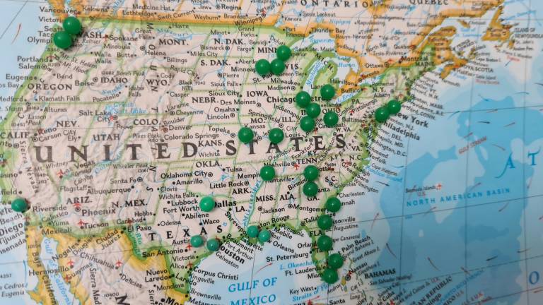 printed map of the US with green pins marking some states