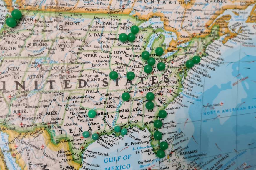 printed map of the US with green pins marking some states